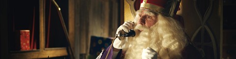een man die een kroon draagt en een telefoon vasthoudt