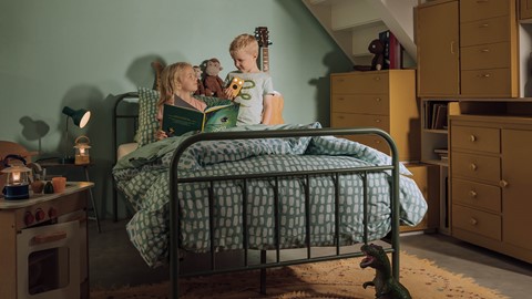 Een jongen en een meisje die een boek in een bed lezen