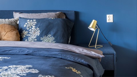 een bed met een gouden lamp op een tafel
