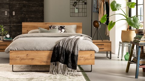 een bed met een deken en een dressoir in een kamer