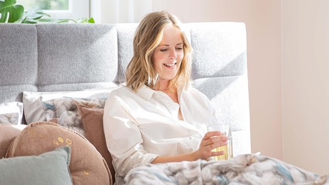 Een vrouw die op een bank zit met een glas vloeistof