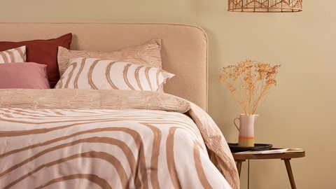 een bed met een vaas met droogbloemen