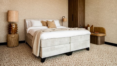 Een bed met kussens en een lamp in een kamer