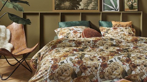 een bed met een bloemendekbed en kussens