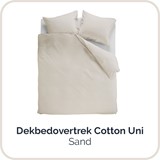 een bed met kussens en een wit laken