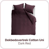 Een bed met een paarse dekbed en kussens