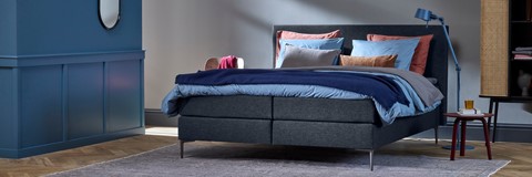 een bed met kussens en een stoel