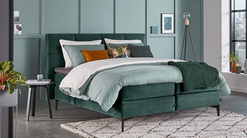 een bed met een groen hoofdeinde